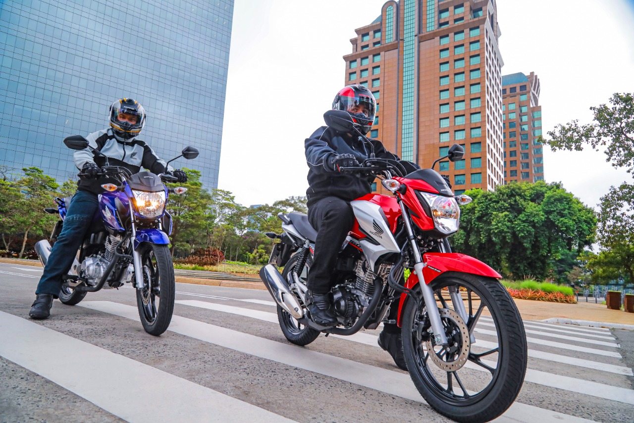 Dois homens pilotando, cada um, uma motocicleta Honda CG 160 2023, nas cores azul e vermelha