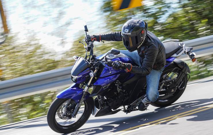 Homem pilotando uma motocicleta Yamaha Fazer 250 2023 na cor azul, na rodovia